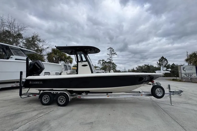 Slide: The Image of 2026 ShearWater 260 Carolina Flare boat on trailer, parked outdoors under cloudy sky. - 8