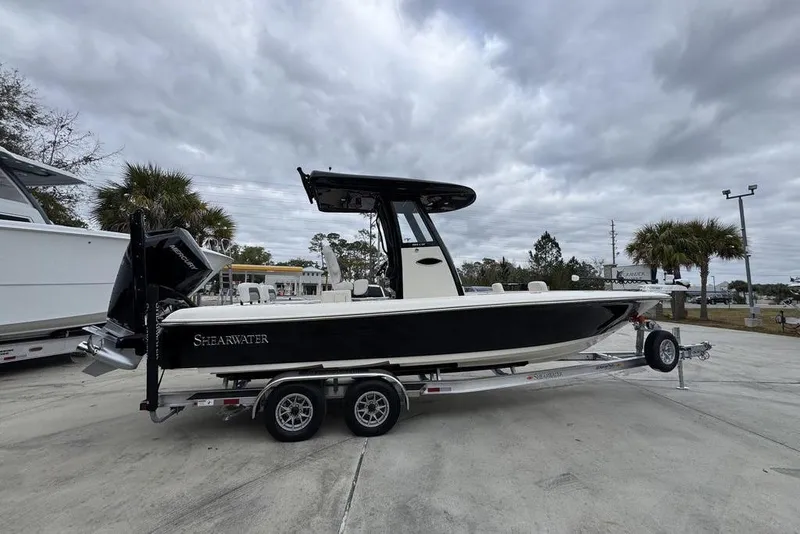 Slide: The Image of 2026 ShearWater 260 Carolina Flare boat on trailer, parked outdoors under cloudy sky. - 9