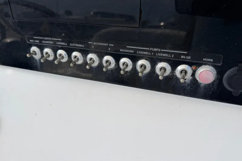 Slide: The Image of Control panel of a 2015 Sportsman Open 212 Center Console boat with switches and buttons. - 16