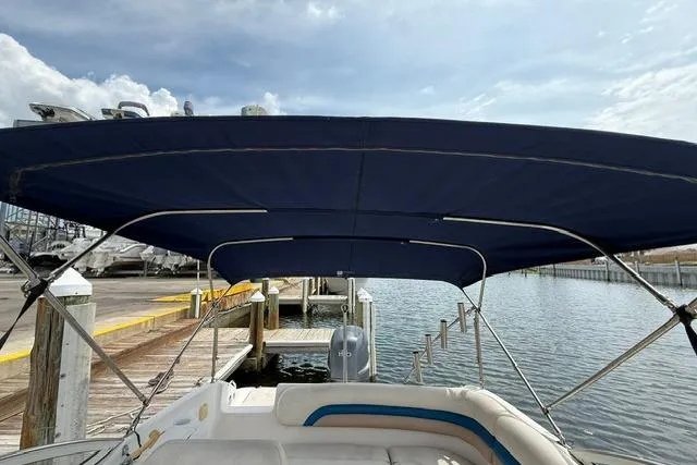 Slide: The Image of 2005 Hurricane SunDeck 217 OB boat with blue canopy at dockside. - 16