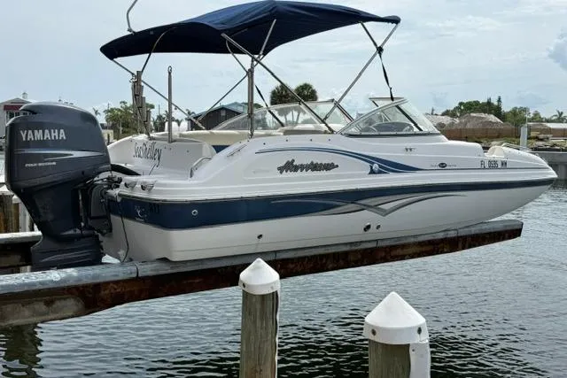 Slide: The Image of 2005 Hurricane SunDeck 217 OB boat with Yamaha engine docked by the water. - 2