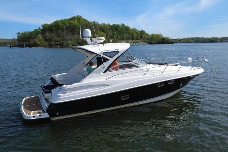Slide: The Image of 2008 Regal 3760 Sportyacht cruising on a serene lake with lush green shoreline. - 10