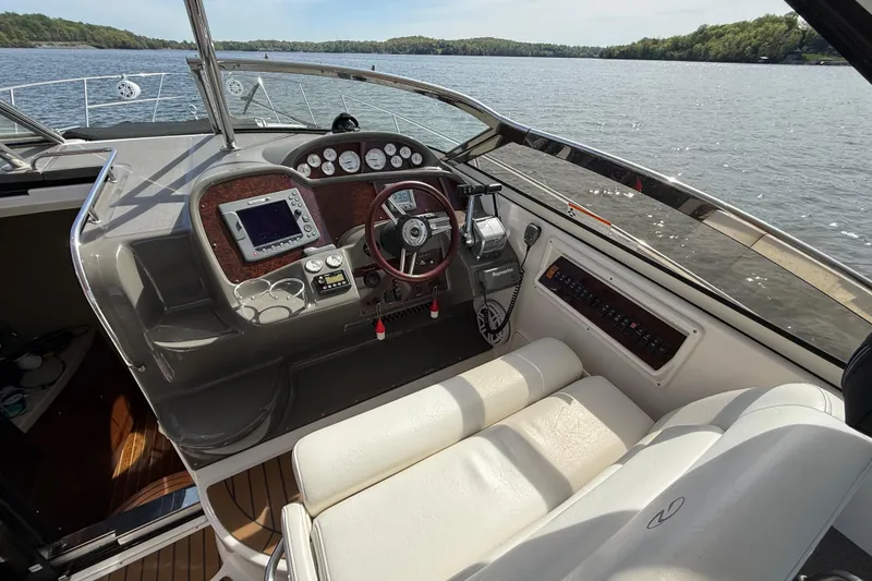 Slide: The Image of 2008 Regal 3760 Sportyacht helm with modern controls, steering wheel, and scenic lake view. - 12