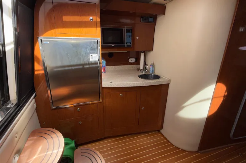 Slide: The Image of 2008 Regal 3760 Sportyacht interior with kitchenette, featuring wood cabinetry and stainless steel fridge. - 21