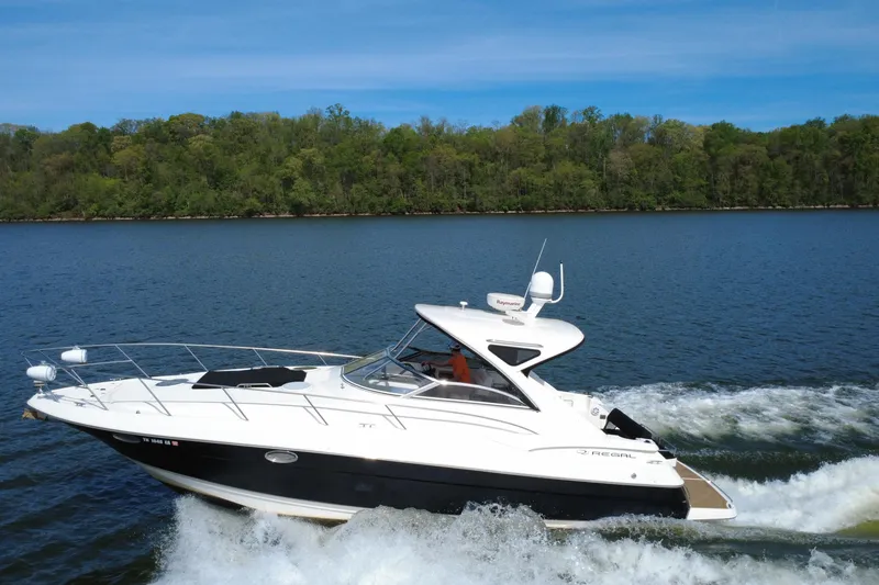 Slide: The Image of 2008 Regal 3760 Sportyacht cruising on a serene lake with lush green shoreline. - 5