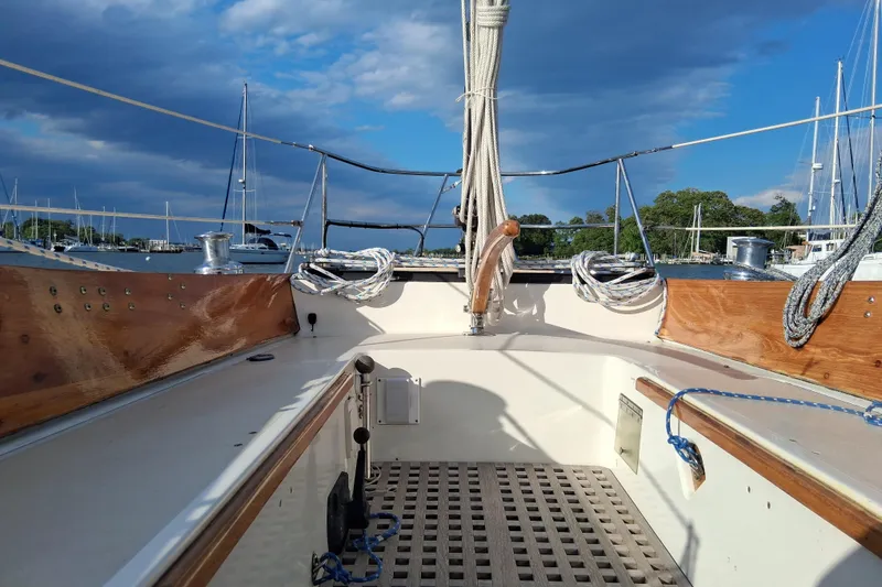Slide: The Image of 1967 Hinckley Pilot 35 sailboat cockpit with wooden trim and ropes, under a partly cloudy sky. - 10