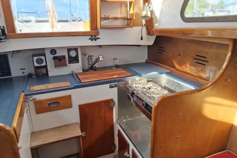 Slide: The Image of Interior of a 1967 Hinckley Pilot 35 sailboat galley with wooden cabinetry and stove. - 14