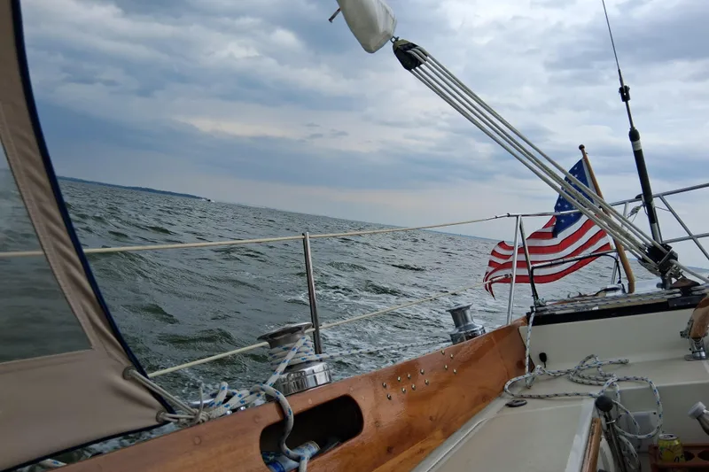 Slide: The Image of Hinckley Pilot 35 sailboat on open water, American flag waving, cloudy sky. - 22