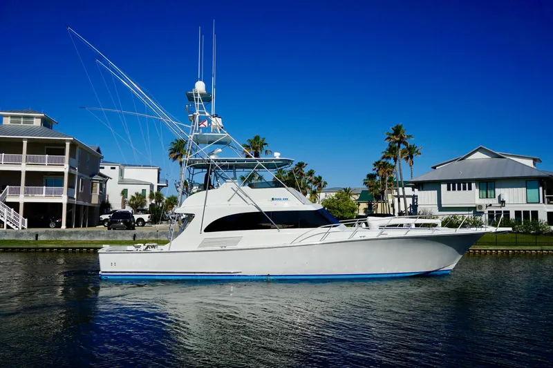 The Image of 1991 G&S 58 yacht docked near waterfront homes under clear blue sky. - 1