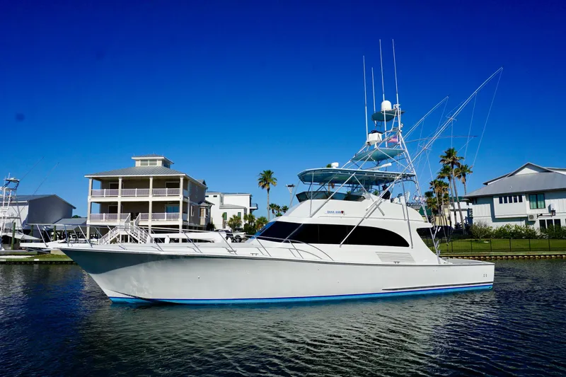 Slide: The Image of 1991 G&S 58 yacht docked near waterfront homes under clear blue sky. - 6