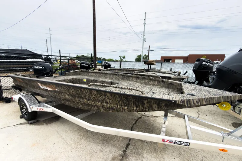 The Image of 2026 Excel 183 Tomahawk boat on trailer, featuring camouflage design and Suzuki outboard motors. - 1