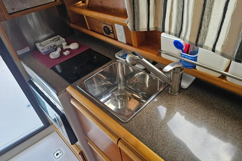 Slide: The Image of 2021 Cutwater C-28 boat kitchen with sink, stove, and countertop essentials. - 17