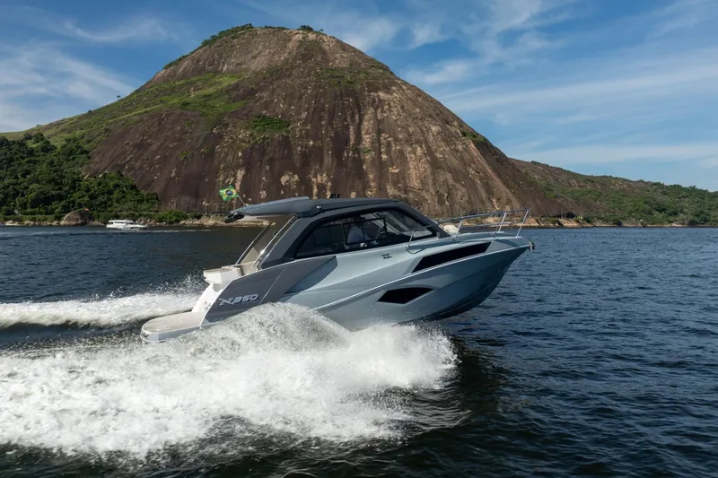 Slide: The Image of 2025 NX Boats NX350 MAXIMUS cruising on water with scenic mountain backdrop. - 10