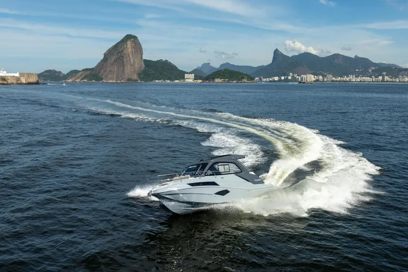 Slide: The Image of 2025 NX Boats NX350 MAXIMUS cruising in scenic coastal waters with mountains in the background. - 12