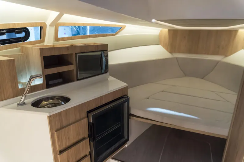 Slide: The Image of Interior of 2025 NX Boats NX350 MAXIMUS, featuring modern kitchenette and cozy sleeping area. - 13