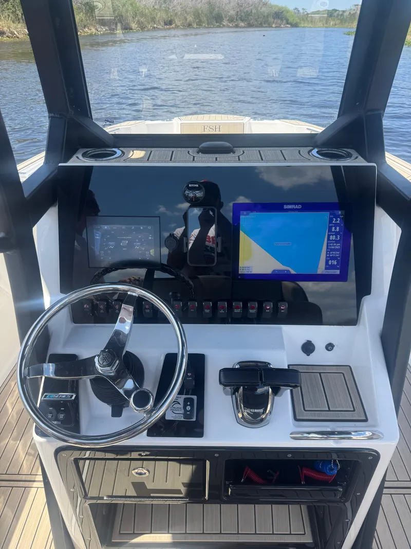 Slide: The Image of 2023 Yamaha Boats 255 FSH Sport E dashboard with navigation display on a calm waterway. - 6