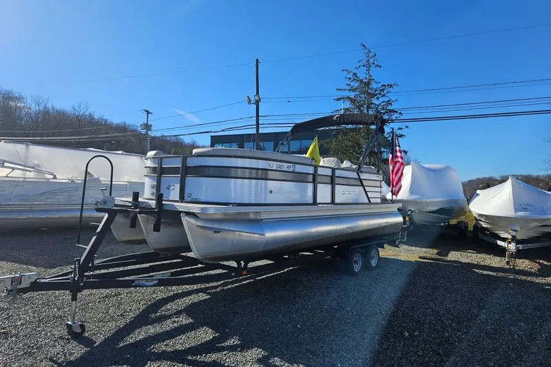 Slide: The Image of 2021 Crest 220 DLX pontoon boat on trailer outdoors. - 1