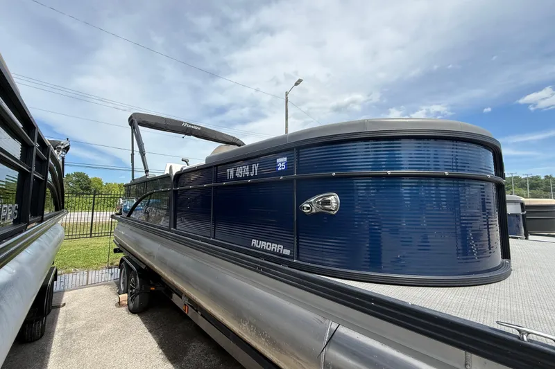 Slide: The Image of 2022 Manitou Aurora LE pontoon boat with sleek blue exterior, parked outdoors. - 2