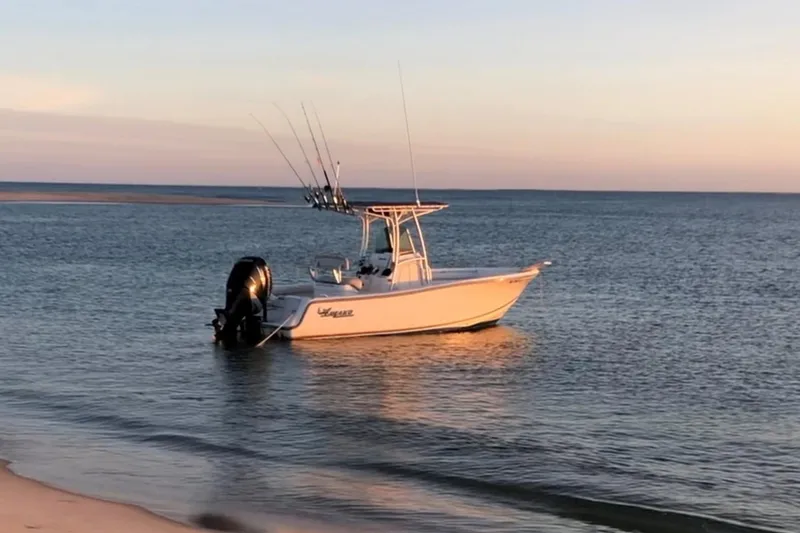 Slide: The Image of 2015 Mako 214 Center Console boat anchored in calm ocean waters at sunset. - 2