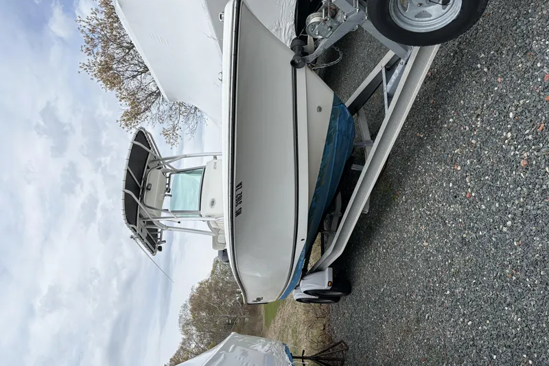 Slide: The Image of 2015 Mako 214 Center Console boat on trailer, parked outdoors under cloudy sky. - 25
