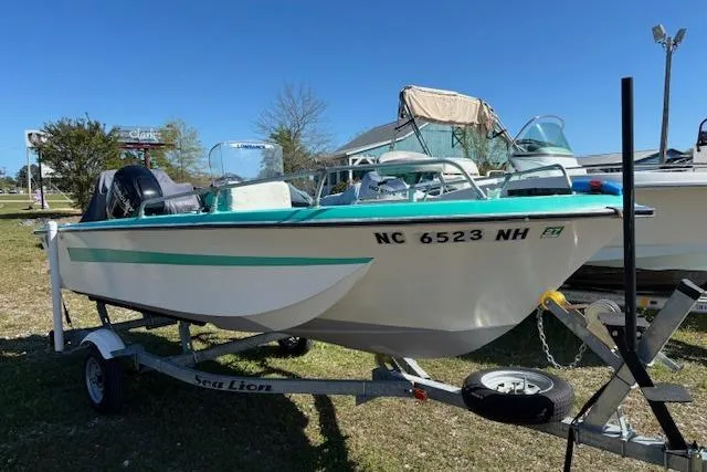 The Image of 1971 Chrysler 15 CC boat on trailer, parked outdoors under clear blue sky. - 1