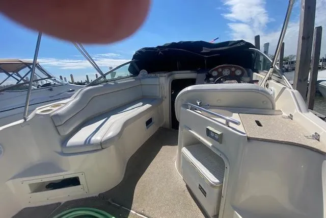 Slide: The Image of 2005 Rinker Fiesta Vee 250 boat interior with seating and dashboard, docked under a clear sky. - 11