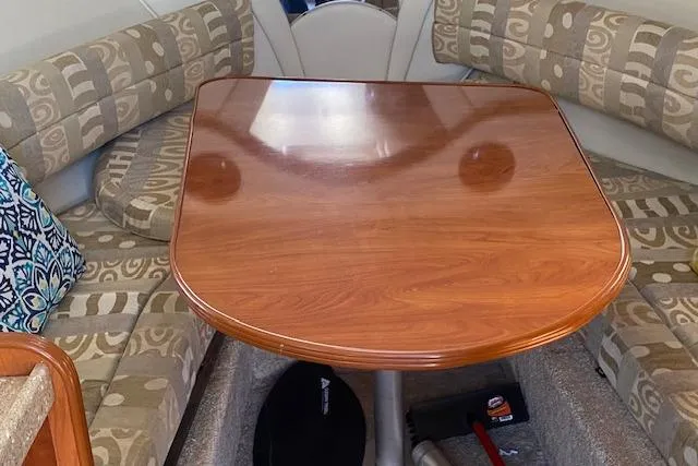 Slide: The Image of 2005 Rinker Fiesta Vee 250 cabin interior with wooden table and patterned seating. - 3