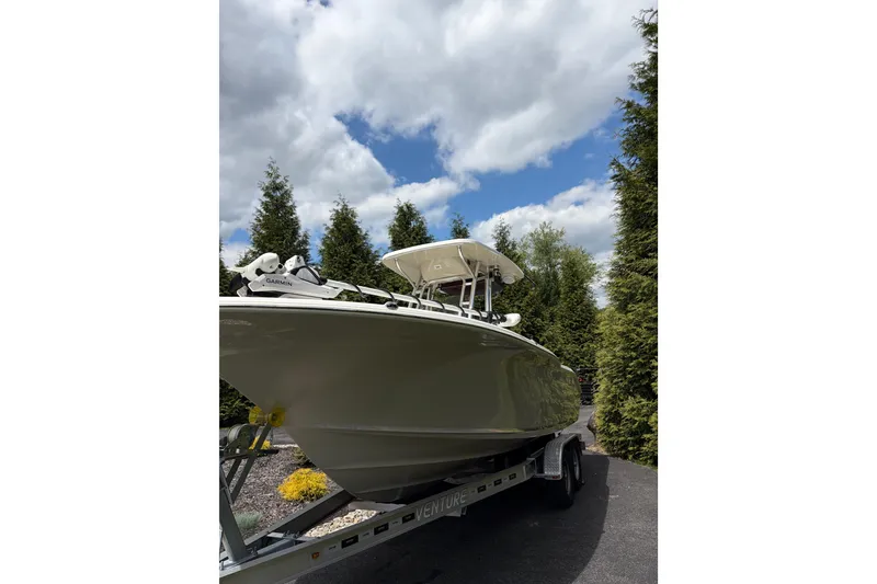 Slide: The Image of 2024 Key West 244 Center Console boat on trailer, surrounded by trees under a cloudy sky. - 1