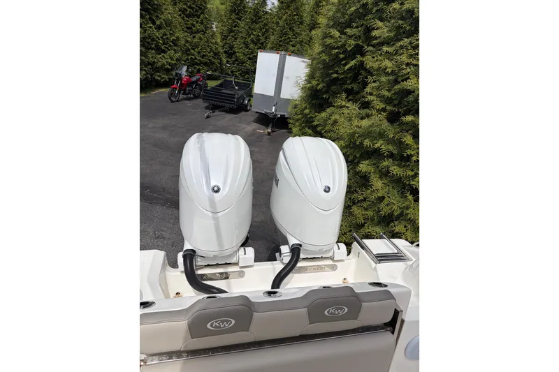 Slide: The Image of 2024 Key West 244 Center Console with dual outboard motors in a driveway setting. - 2