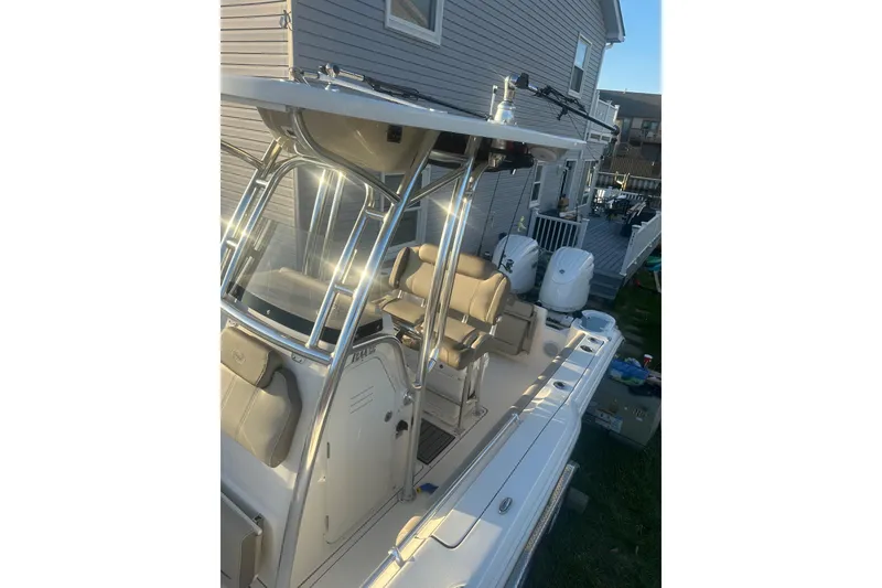 Slide: The Image of 2024 Key West 244 Center Console boat with dual engines, parked beside a house. - 5