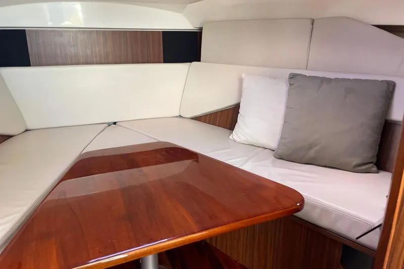Slide: The Image of Interior cabin of 2016 Pursuit OS 325 Offshore with cushioned seating and wooden table. - 7