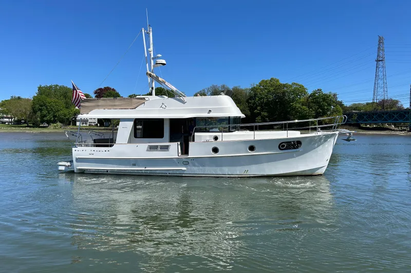 The Image of 2018 Beneteau Swift Trawler 44 cruising on a calm river under a clear blue sky. - 0