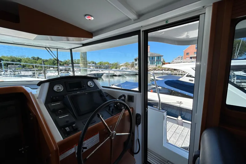 Slide: The Image of Interior view of 2018 Beneteau Swift Trawler 44 helm, overlooking marina. - 13