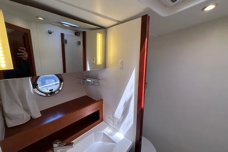 Slide: The Image of Interior of 2018 Beneteau Swift Trawler 44 bathroom with mirror and porthole. - 21