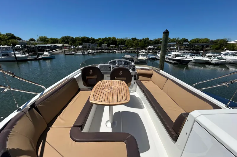 Slide: The Image of 2018 Beneteau Swift Trawler 44 with spacious seating and table, docked in a marina. - 22