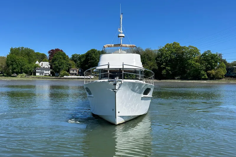 Slide: The Image of 2018 Beneteau Swift Trawler 44 on calm water, surrounded by lush greenery. - 3