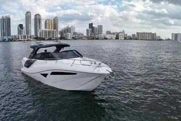 Slide: The Image of 2025 NX Boats NX360 SPORT COUPE on water with city skyline backdrop. - 3