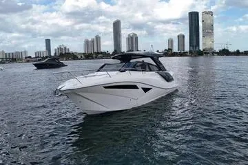 Slide: The Image of 2025 NX Boats NX360 Sport Coupe cruising on a city waterfront with skyscrapers in the background. - 6