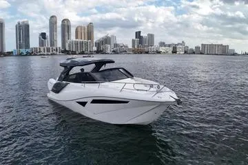 Slide: The Image of 2025 NX Boats NX360 Sport Coupe on water with city skyline backdrop. - 8