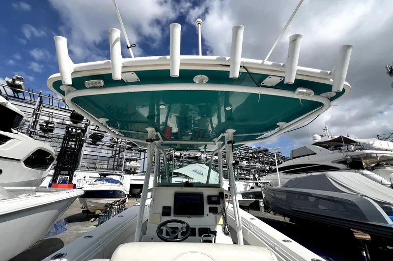 Slide: The Image of 2012 Contender 35 LS boat with teal canopy, docked among other vessels under a cloudy sky. - 30