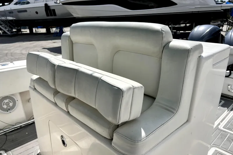 Slide: The Image of White leather seating on a 2012 Contender 35 LS boat, docked with visible engines. - 37