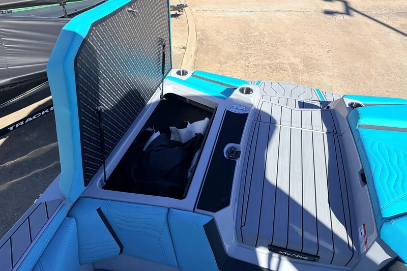 Slide: The Image of 2026 Nautique Super Air Nautique G23 boat storage compartment with open hatch, blue and gray interior. - 53