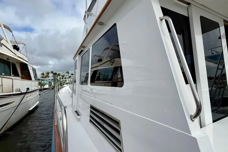 Slide: The Image of 2002 Legacy 52 yacht docked, showcasing sleek white exterior and reflective windows. - 17