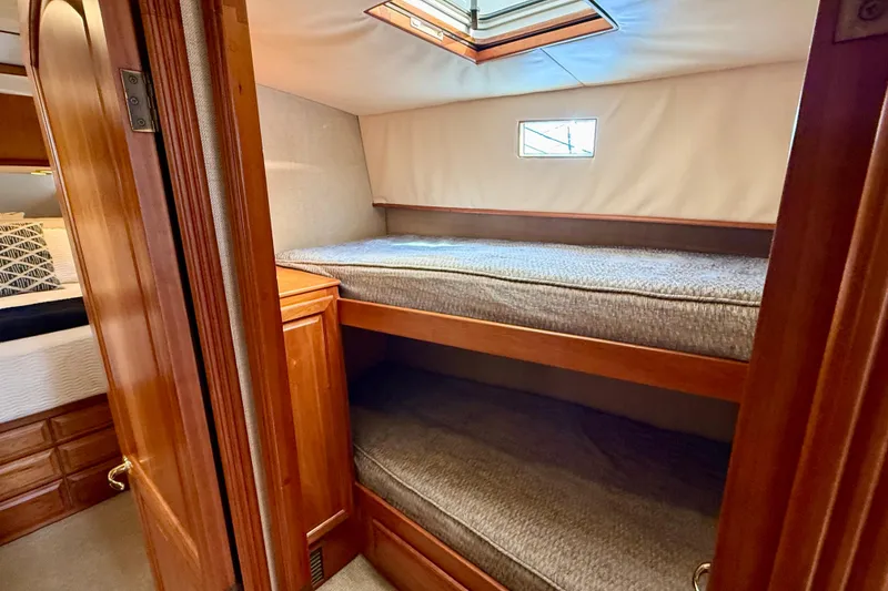 Slide: The Image of Bunk beds in a 2002 Legacy 52 yacht cabin with wooden interior and small window. - 58