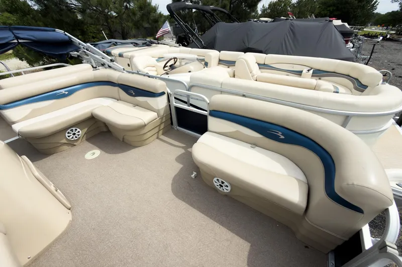 Slide: The Image of 2012 Bennington 22 SSL pontoon boat with beige seating and blue accents, docked outdoors. - 19