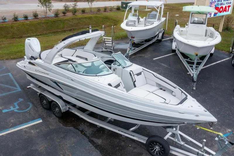 Slide: The Image of 2026 Crownline 318 XSS boat on trailer, parked in a lot with other boats. - 2