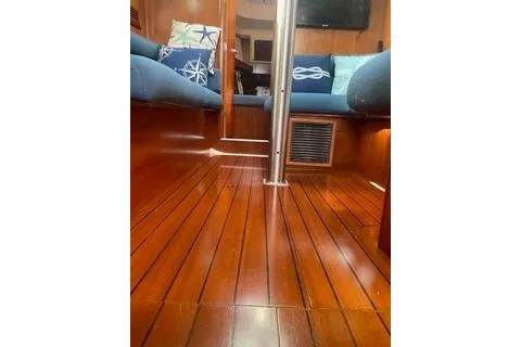 Slide: The Image of Interior of 2002 Beneteau Oceanis Clipper 361 with polished wood flooring and nautical-themed cushions. - 17