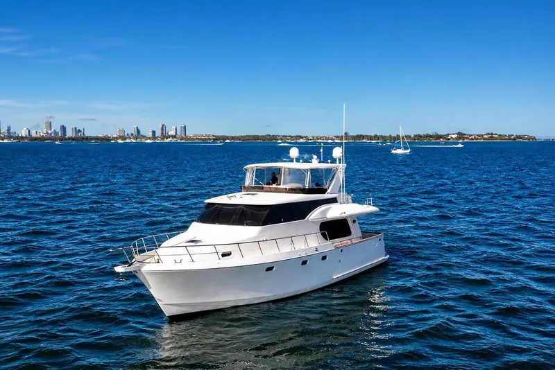 The Image of 2005 Symbol 58 Pilothouse yacht cruising on blue ocean near city skyline. - 1