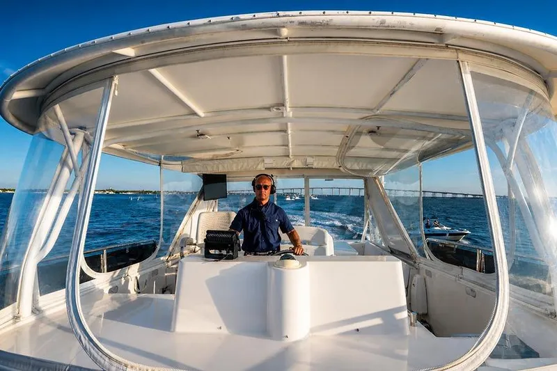 Slide: The Image of Person steering a 2005 Symbol 58 Pilothouse boat on open water. - 54