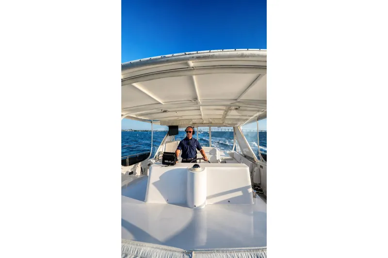 Slide: The Image of Person steering a 2005 Symbol 58 Pilothouse yacht on open water under clear blue skies. - 55